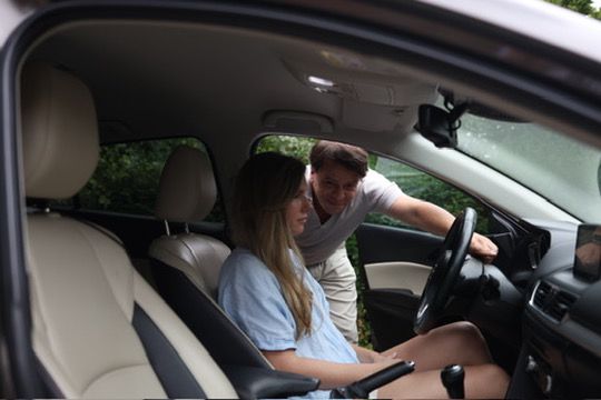 Rijinstructeur Slava geeft uitleg terwijl een leerling achter het stuur van de lesauto zit