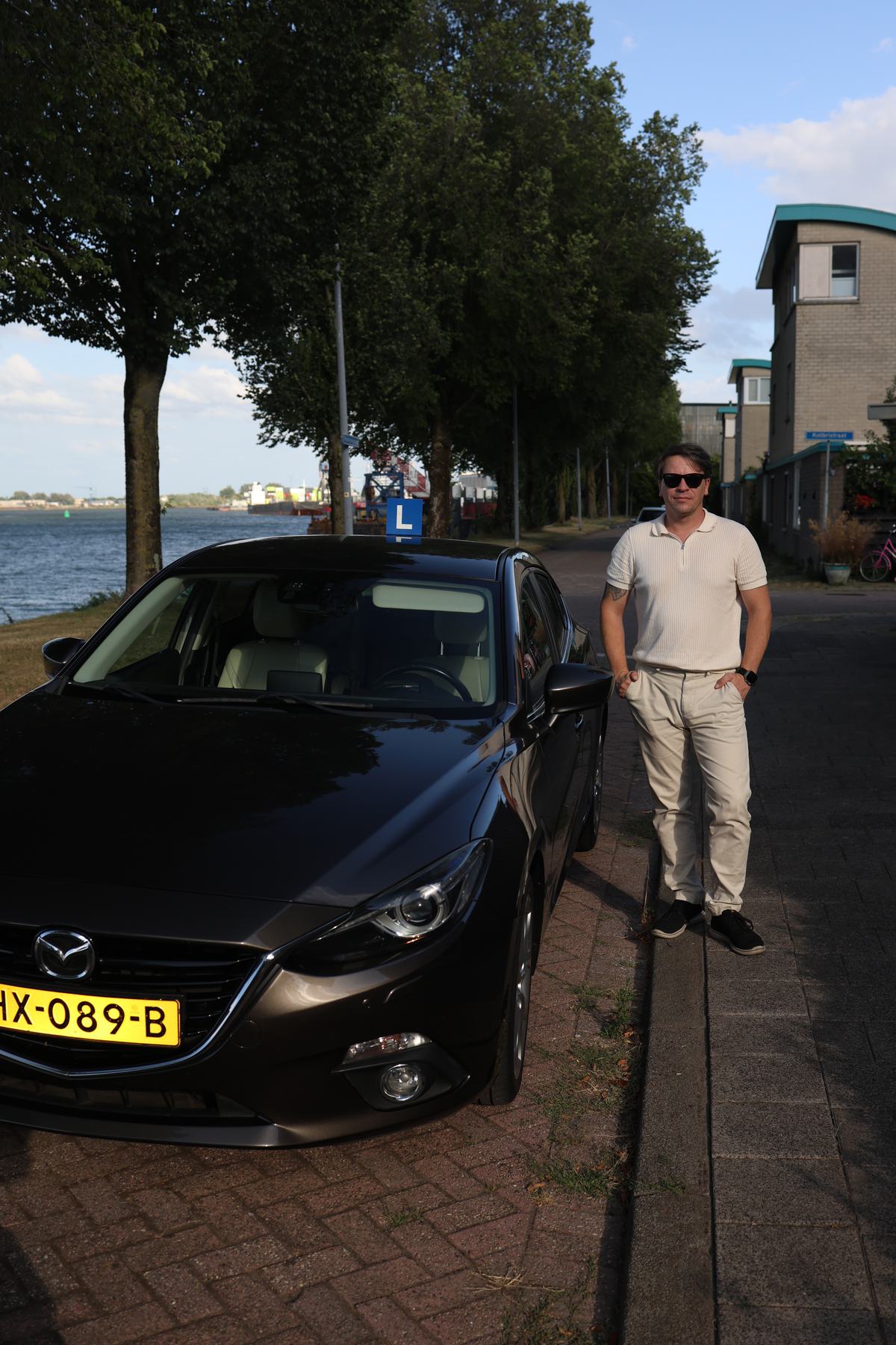 Slava Smirnov, rijinstructeur en eigenaar van Nova Drive Rijschool, naast zijn lesauto